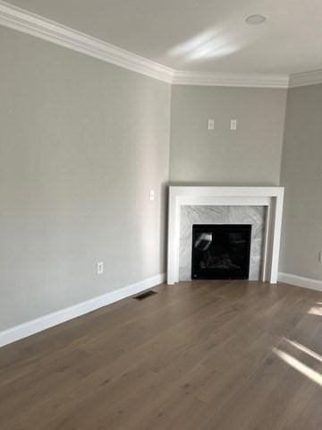 unfurnished living room featuring a high end fireplace, ornamental molding, and dark wood-type flooring