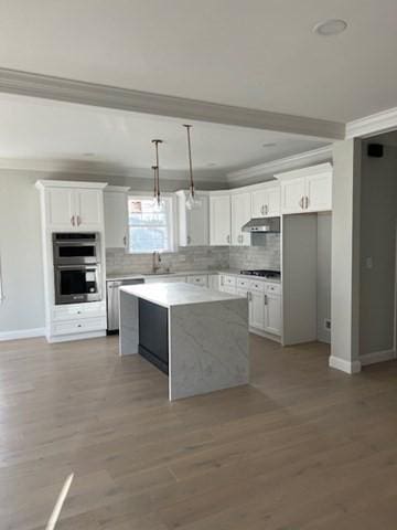 kitchen with appliances with stainless steel finishes, crown molding, a kitchen island, white cabinetry, and decorative light fixtures