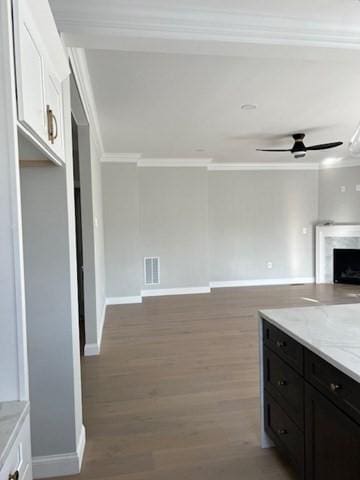 kitchen featuring crown molding, light stone countertops, ceiling fan, dark hardwood / wood-style flooring, and white cabinets