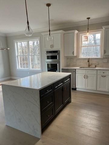 kitchen featuring stainless steel appliances, a center island, pendant lighting, white cabinets, and sink