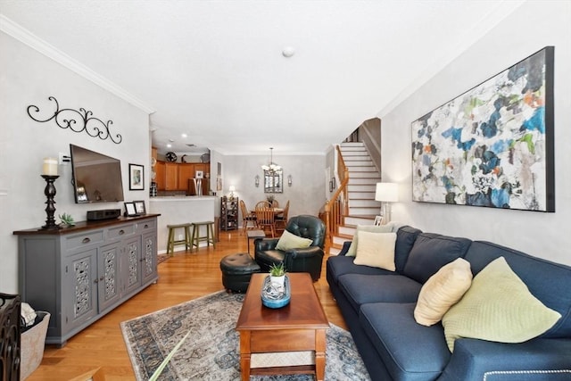 living room with ornamental molding, light hardwood / wood-style floors, and a notable chandelier