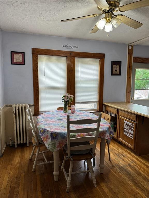 194 Fells Ave, Medford, MA 02155 - dining area with radiator heating unit, hardwood / wood-style flooring, a textured ceiling, and a ceiling fan