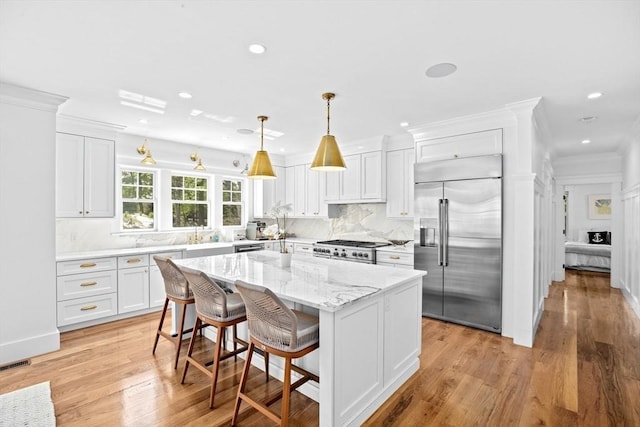 kitchen with stainless steel built in fridge, light wood finished floors, white cabinets, tasteful backsplash, and recessed lighting