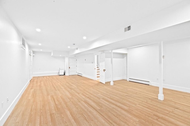finished below grade area featuring a baseboard heating unit, light wood-type flooring, baseboards, and recessed lighting