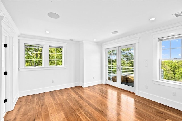 spare room featuring healthy amount of natural light, ornamental molding, baseboards, french doors, and wood finished floors