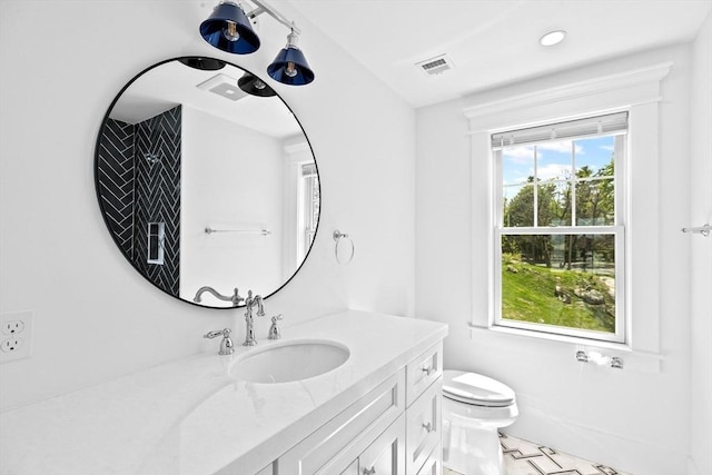 bathroom with toilet, vanity, and recessed lighting