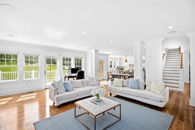 living area featuring ornate columns, stairway, ornamental molding, light wood-type flooring, and recessed lighting