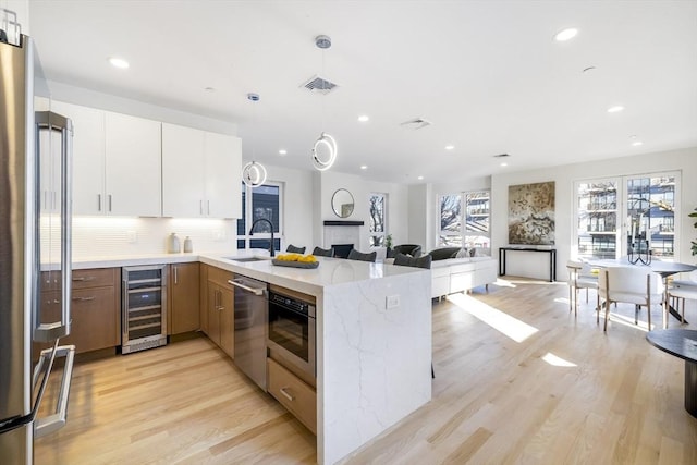 kitchen featuring white cabinetry, sink, wine cooler, light stone counters, and appliances with stainless steel finishes