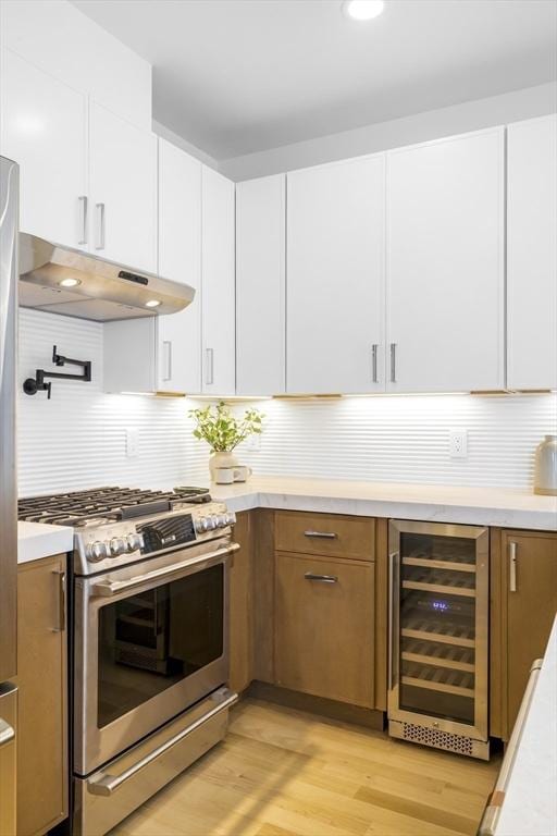 kitchen with tasteful backsplash, beverage cooler, light hardwood / wood-style flooring, high end stainless steel range, and white cabinets