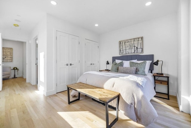 bedroom featuring light wood-type flooring and multiple closets