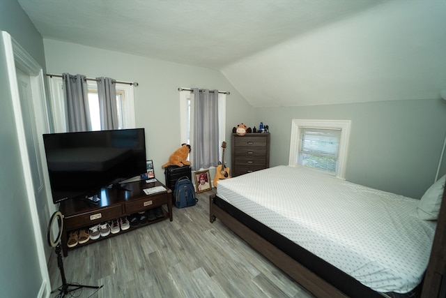 bedroom with vaulted ceiling, multiple windows, and light hardwood / wood-style floors