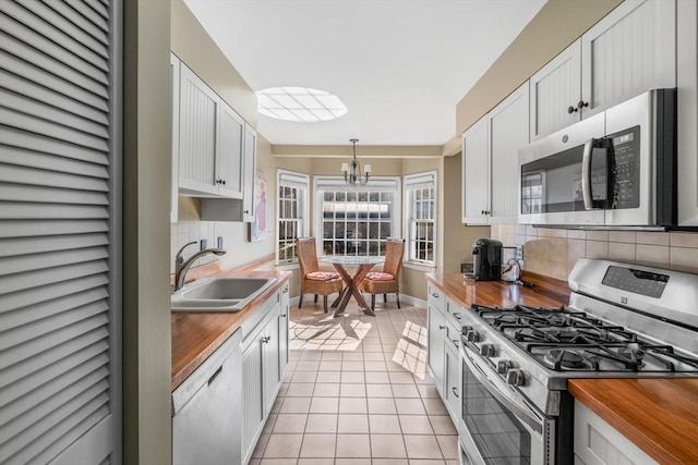 30 N Stone Ml Unit 1211, Dedham, MA 02026 - kitchen featuring an inviting chandelier, a sink, wood counters, appliances with stainless steel finishes, and backsplash