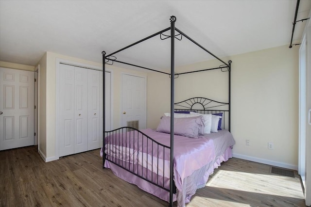 bedroom with visible vents, baseboards, and wood finished floors