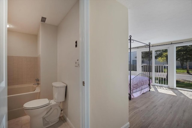 full bathroom featuring visible vents, wood finished floors, toilet, baseboards, and a tub to relax in