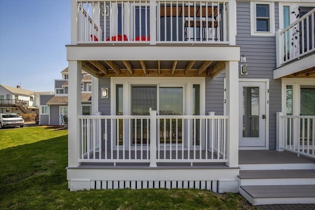 rear view of house featuring a lawn and a balcony