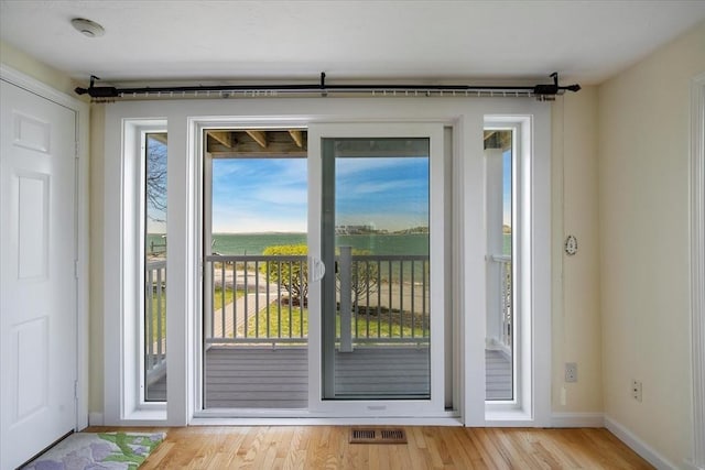 doorway featuring baseboards, light wood finished floors, and visible vents