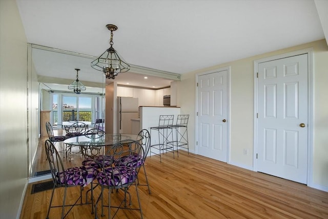 dining space with baseboards, light wood finished floors, and a chandelier