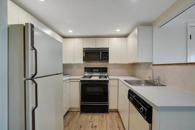 kitchen featuring decorative backsplash, white appliances, light wood-style floors, light countertops, and a sink
