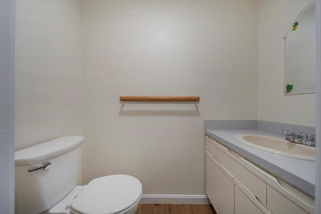 bathroom with toilet, baseboards, wood finished floors, and vanity