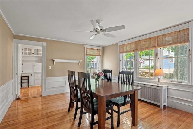 57 Highland St, Holden, MA 01520 - dining space with radiator heating unit, ceiling fan, a decorative wall, light wood-style floors, and wainscoting
