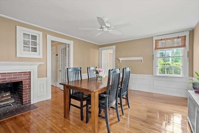 57 Highland St, Holden, MA 01520 - dining area featuring wood finished floors, ornamental molding, a ceiling fan, a wainscoted wall, and a brick fireplace