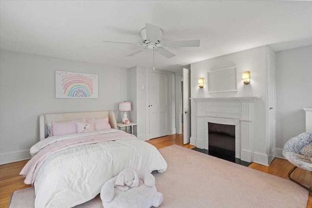 57 Highland St, Holden, MA 01520 - bedroom featuring wood finished floors, baseboards, a fireplace with flush hearth, and a ceiling fan