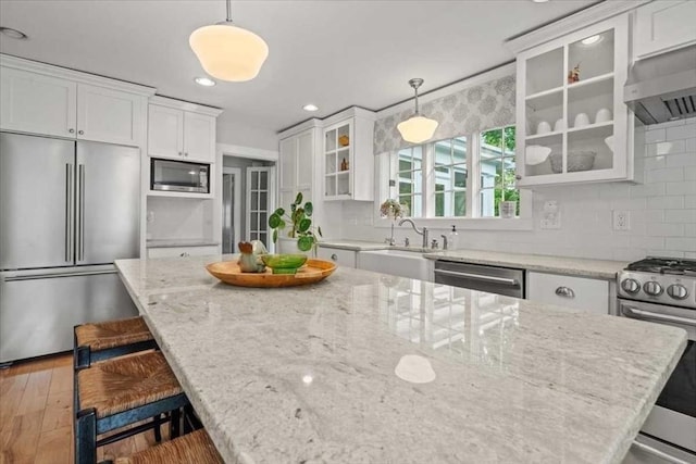 57 Highland St, Holden, MA 01520 - kitchen with appliances with stainless steel finishes, white cabinetry, ventilation hood, a breakfast bar area, and recessed lighting