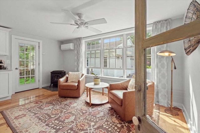 57 Highland St, Holden, MA 01520 - living area featuring an AC wall unit, a wood stove, wood finished floors, and baseboards