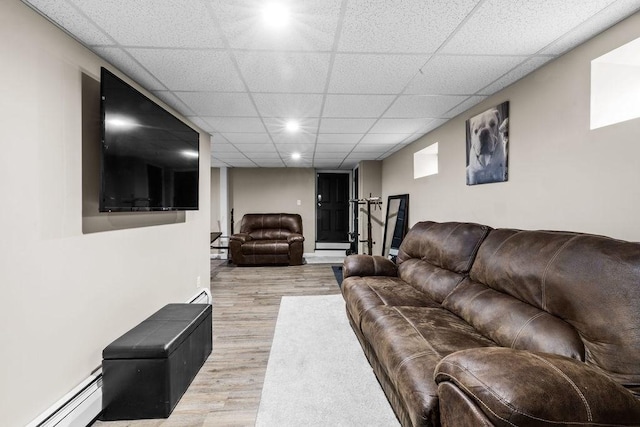 living room with a baseboard radiator, light hardwood / wood-style floors, and a paneled ceiling