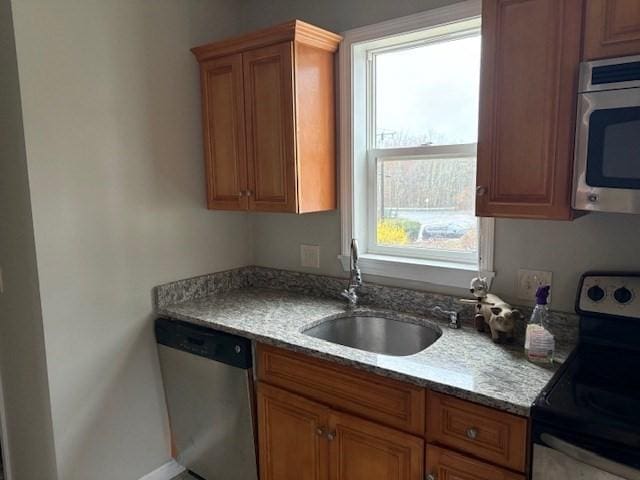 kitchen featuring a healthy amount of sunlight, brown cabinetry, a sink, and appliances with stainless steel finishes