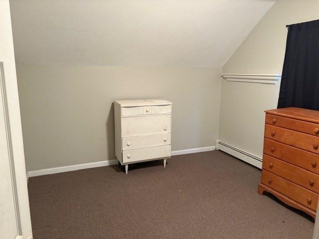 interior space with dark carpet, a baseboard radiator, and vaulted ceiling