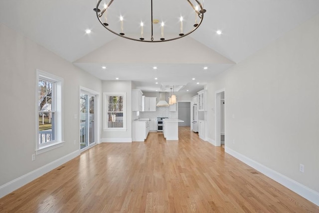 unfurnished living room with a chandelier, light wood-type flooring, and lofted ceiling