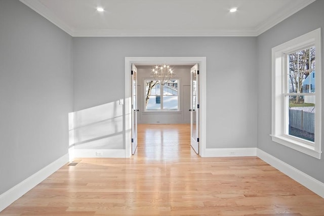 unfurnished room featuring a wealth of natural light, crown molding, light hardwood / wood-style flooring, and a notable chandelier