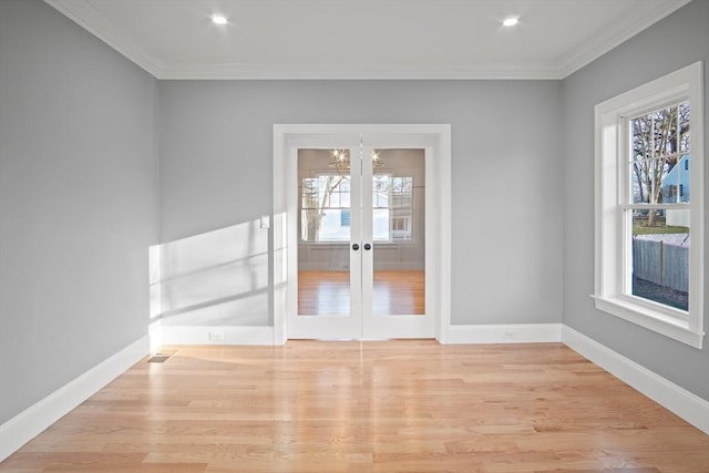 unfurnished room featuring an inviting chandelier, light hardwood / wood-style floors, crown molding, and french doors