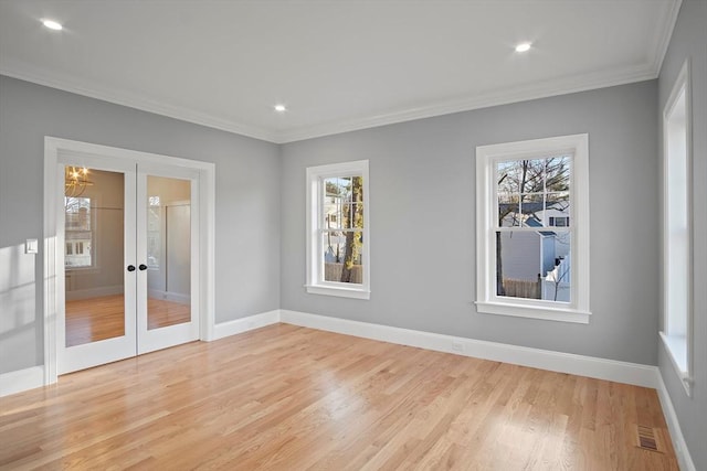 empty room featuring plenty of natural light, light hardwood / wood-style flooring, crown molding, and french doors