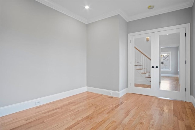 empty room featuring crown molding, french doors, and light hardwood / wood-style floors