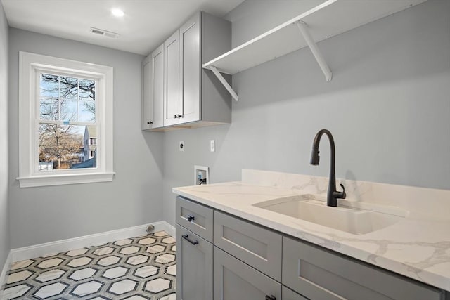 clothes washing area featuring hookup for an electric dryer, plenty of natural light, cabinets, and sink