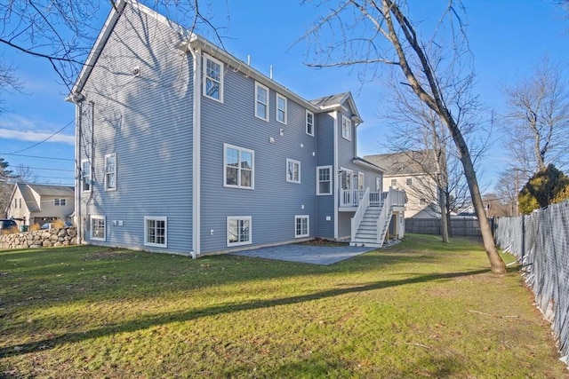 back of house featuring a wooden deck, a patio area, and a lawn