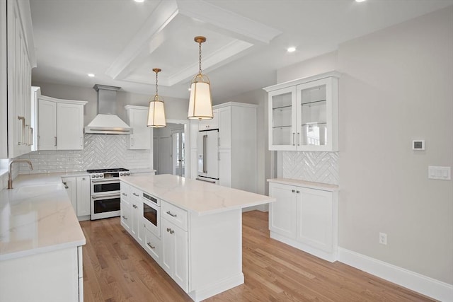 kitchen featuring custom exhaust hood, a center island, stainless steel stove, high end fridge, and white cabinetry