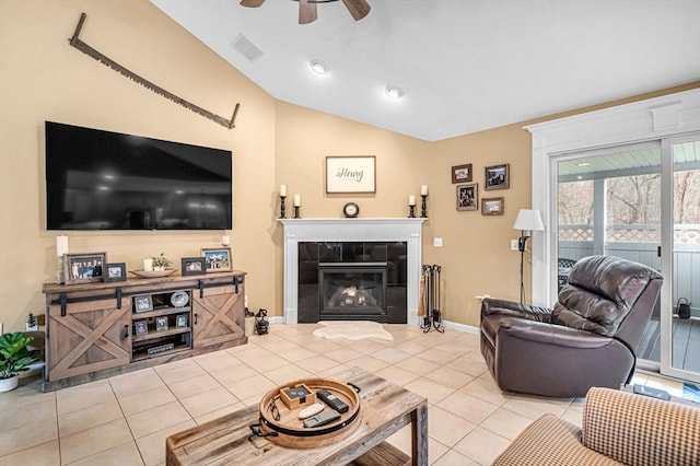 living room with a tile fireplace, ceiling fan, vaulted ceiling, and light tile patterned floors