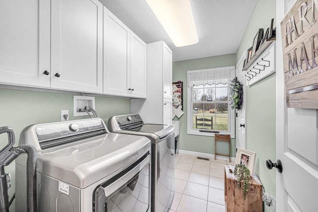 clothes washing area featuring washer and dryer, cabinets, and light tile patterned floors