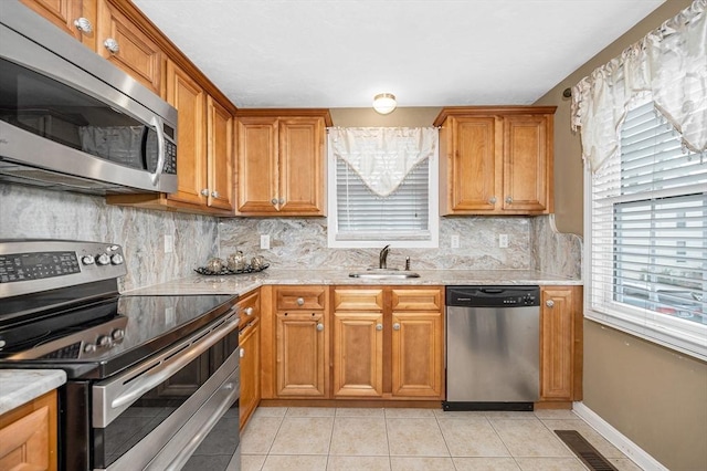 14 Watson St Unit 4, Lowell, MA 01852 - kitchen featuring stainless steel appliances, tasteful backsplash, light tile patterned floors, and brown cabinets