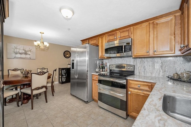 14 Watson St Unit 4, Lowell, MA 01852 - kitchen featuring stainless steel appliances, light tile patterned flooring, a chandelier, brown cabinets, and tasteful backsplash