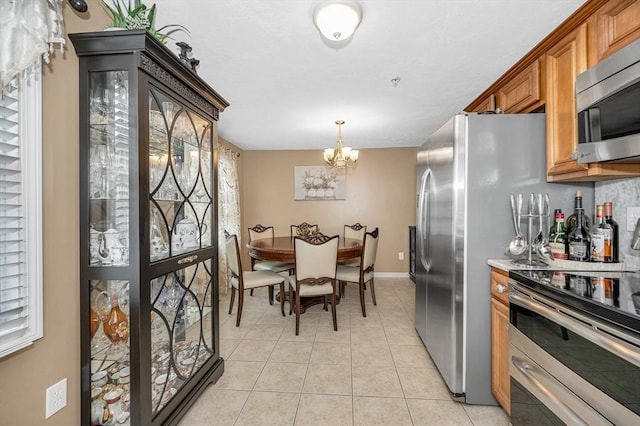 14 Watson St Unit 4, Lowell, MA 01852 - kitchen with appliances with stainless steel finishes, brown cabinets, a chandelier, light tile patterned flooring, and light countertops