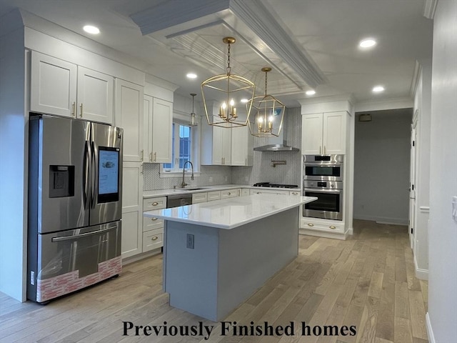 kitchen with stainless steel appliances, light wood-type flooring, wall chimney exhaust hood, and a chandelier