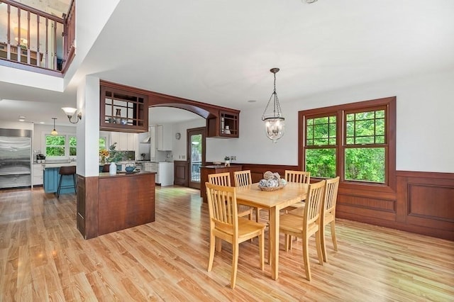 32 Witham St Unit B, Gloucester, MA 01930 - dining area with healthy amount of natural light, wainscoting, light wood-style floors, arched walkways, and a chandelier