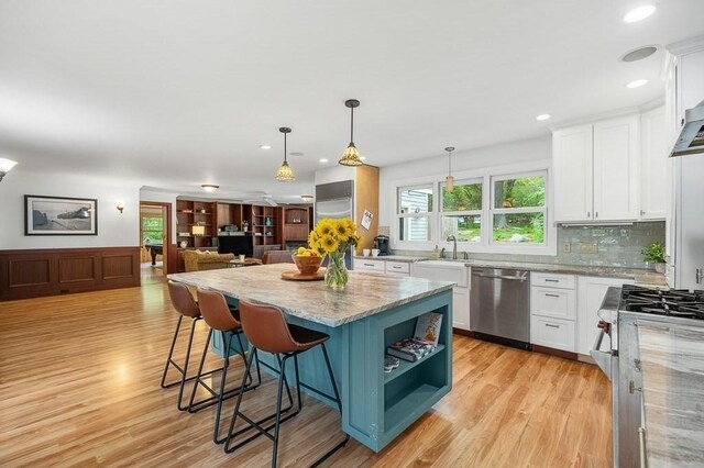 32 Witham St Unit B, Gloucester, MA 01930 - kitchen with appliances with stainless steel finishes, white cabinetry, a kitchen island, light stone countertops, and recessed lighting