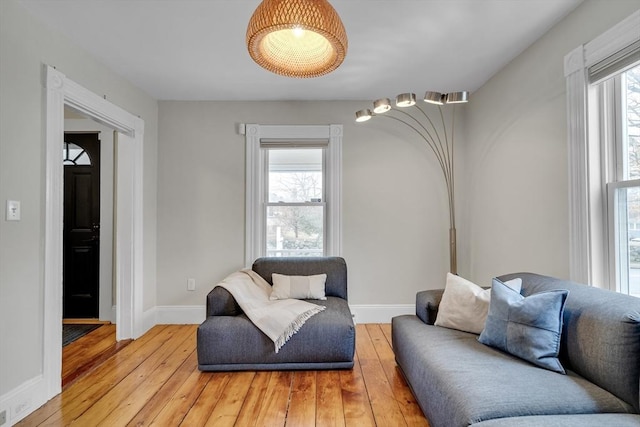 living area with baseboards, light wood-style floors, and a healthy amount of sunlight