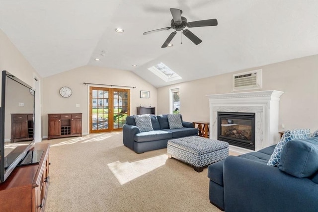 carpeted living room featuring an AC wall unit, ceiling fan, a wealth of natural light, and vaulted ceiling with skylight