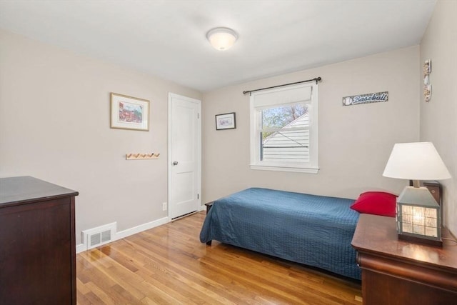 bedroom featuring baseboards, wood finished floors, and visible vents